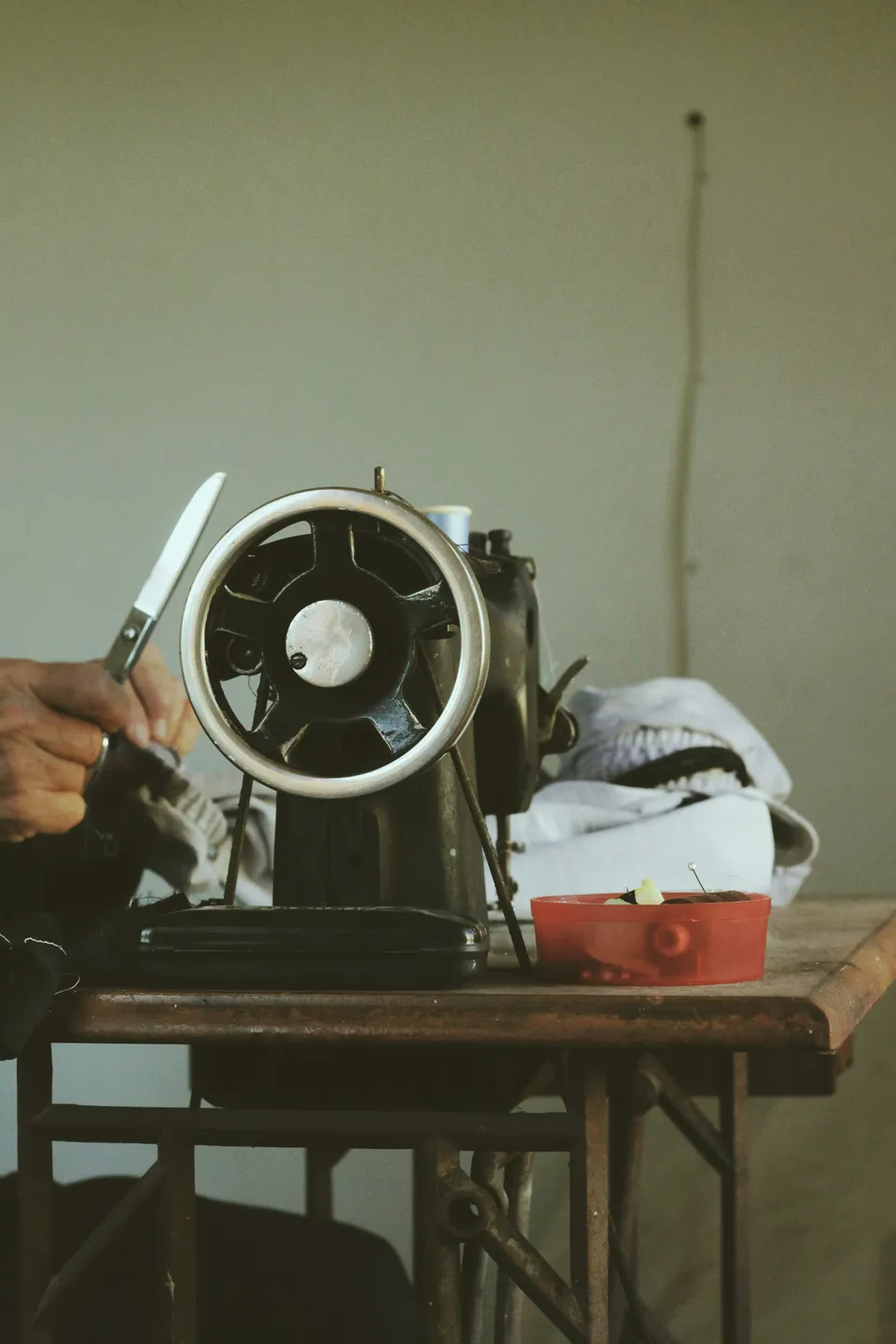 A tailor working at a vintage sewing machine on a wooden worktable